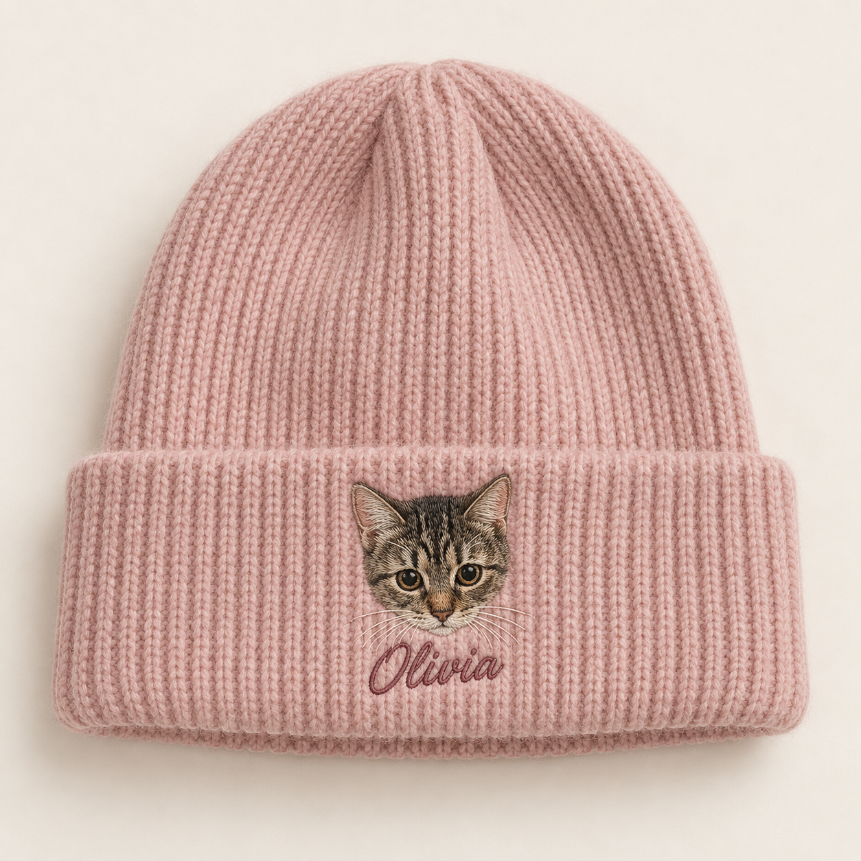 Dusty rose knitted beanie with an embroidered cat face and Olivia lettering
